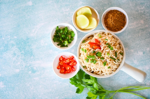 Instant noodles cooking tasty eating with bowl noodles bowl with vegetable spring onion lemon lime lettuce celery and chili on table food noodle soup