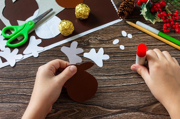 Instruction step 7 Funny Gift with candy Christmas deer on a wooden table Handmade