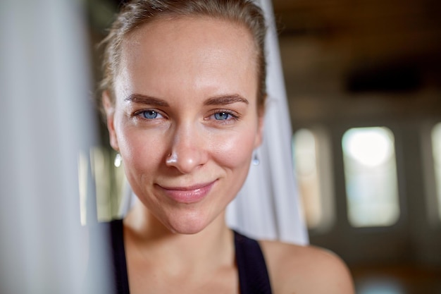 Instructor in aerial yoga portrait closeup hipster girl with an expressive look yoga trainer posing