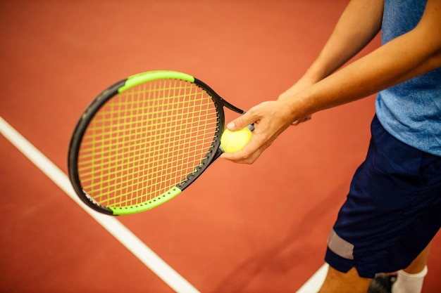 Instructor or coach teaching how to play tennis on a court indoor