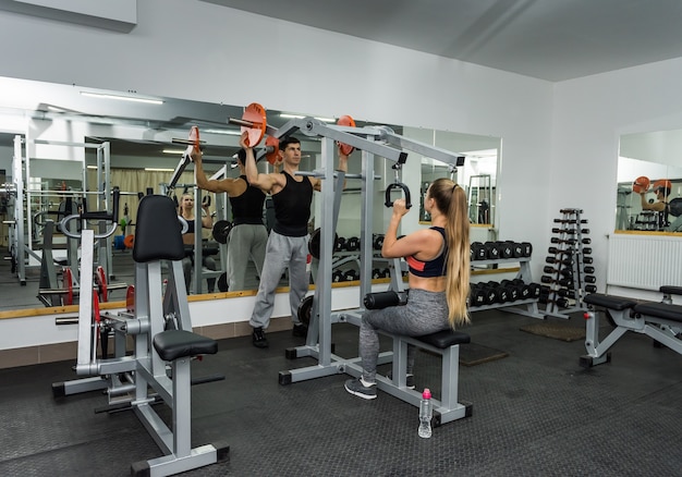 Instructor helping woman lift sport equipment in gym