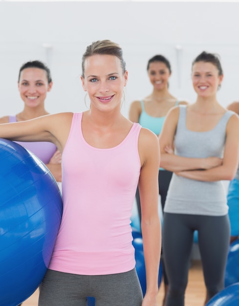 Instructor holding exercise ball with fitness class in background