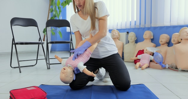 Instructor performs CPR on baby training doll. Woman instructor show how to do CPR on a doll dummy for cardiopulmonary reanimation training.