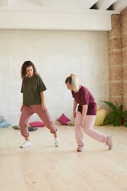 Instructor showing the movements to young woman and teaching her to dance in health club