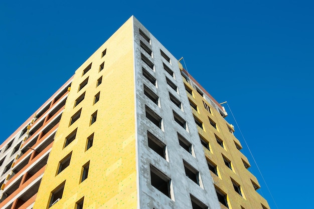 Insulation of the wall of a monolithic house under construction with yellow insulation