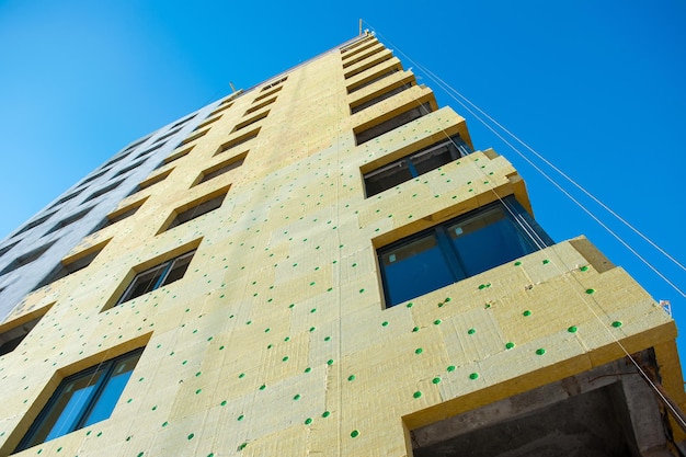 Insulation of the wall of a monolithic house under construction with yellow insulation