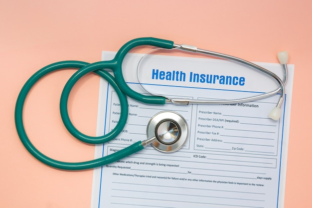 Insurance claim form and stethoscope on light orange background