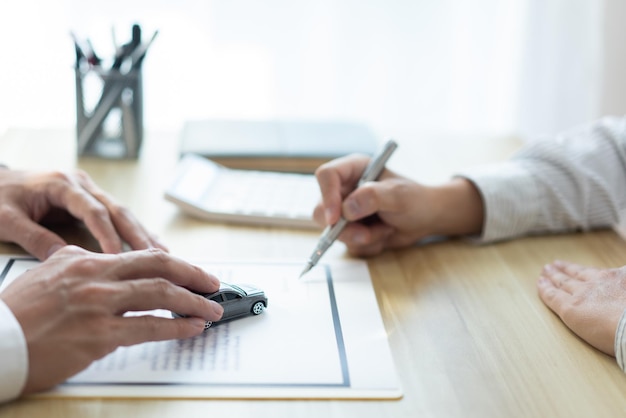 Insurance concept the customer signing his name on the contract while the dealer giving more details