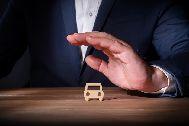 Insurance professional covering a car with his hand Protection against unforeseen events on the road