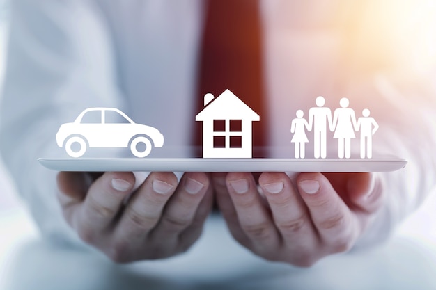 Insurer protecting a family, a house and a car with his hands; multiple exposure