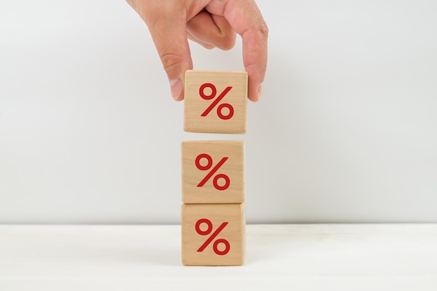 Interest rate financial and mortgage rates concept Hand putting wood cube block increasing on top with icon percentage symbol upward direction