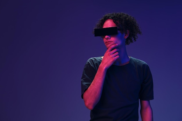 Interested stylish tanned curly man in black tshirt trendy eyewear posing isolated on color pink blue studio background Cool fashion offer Virtual Reality New Collection concept Copy space for ad