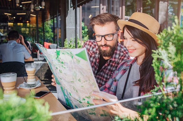 Interested young man and woman sit and look at map she holds