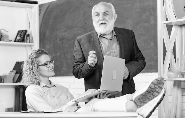 Interesting lesson senior teacher and woman at school lesson student and tutor with laptop pass exam teachers room modern school education happy student girl with tutor man at blackboard