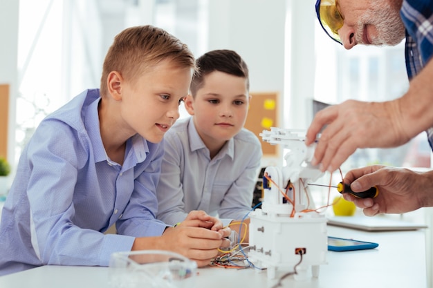 Interesting lesson. Smart nice boys sitting at the desk while looking at their teacher