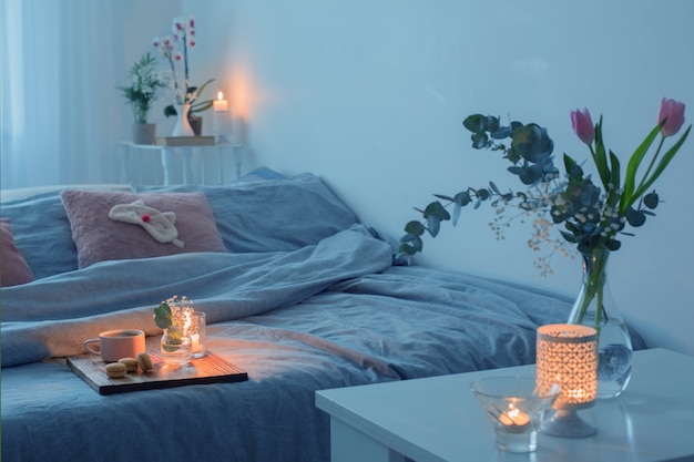 Interior of bedroom with flowers, candles and cup of tea