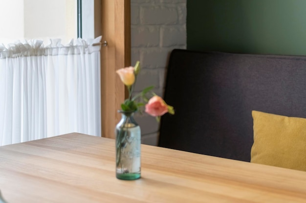 Interior of the cafe Bottle with fresh flowers on table in cafe on sofa and window background Cozy atmosphere in coffee shop