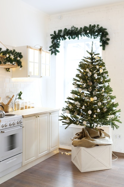 Interior of a Christmas light kitchen decorated with a Christmas tree and garlands