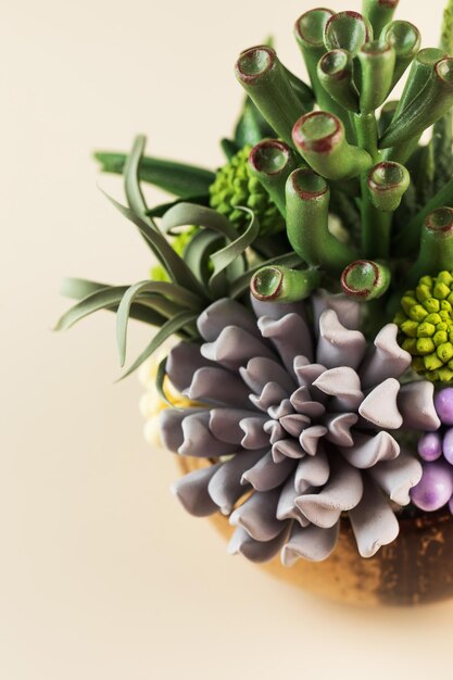 Interior composition of green plants and succulents made by hand from polymer clay on a beige backgr...