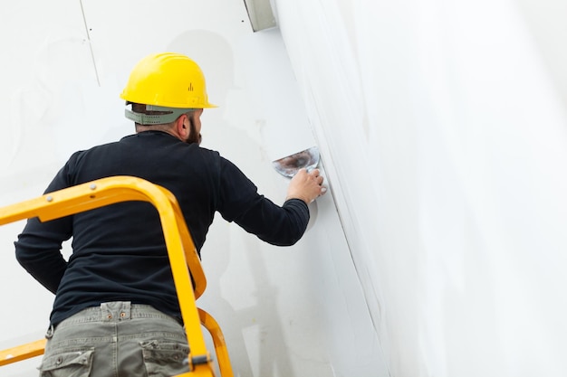 Photo interior construction worker plastering gypsum board wall