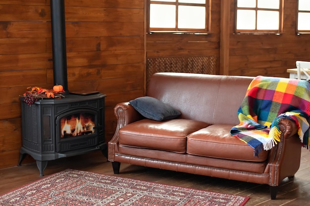 Interior cozy living room with wood burning stove inside, comfortable sofa and carpet on floor