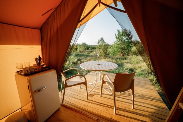 Interior of Cozy open glamping tent with light inside during sunset Luxury camping tent for outdoor summer holiday and vacation Lifestyle concept