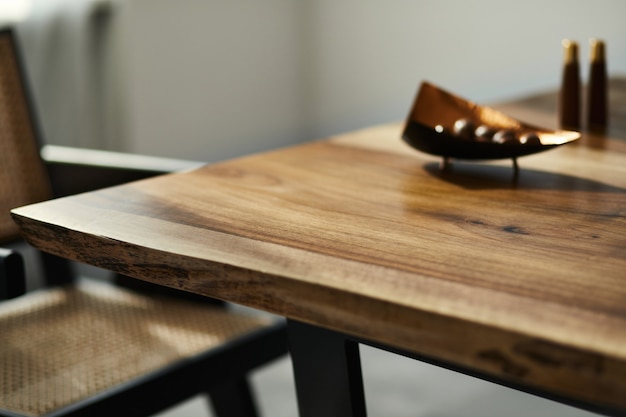 Interior design of stylish dining room interior with family wooden table, modern chairs, plate with nuts, salt and pepper shakers