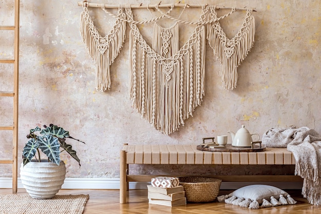 Interior design of stylish living room with beige chaise longue, pillows, lantern, macrame, dried flower, tea pot on the tray, decoration and elegant personal accessories in oriental concept.