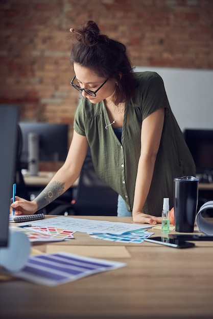 Interior designer or architect in casual wear with messy hairdo making notes while working on new