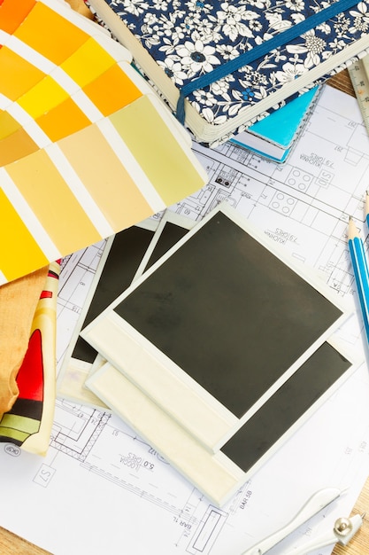 Interior designer working desktop, an architectural plan of the house,  color palette and fabric samples in yellow shades, copy space on instant empty photos