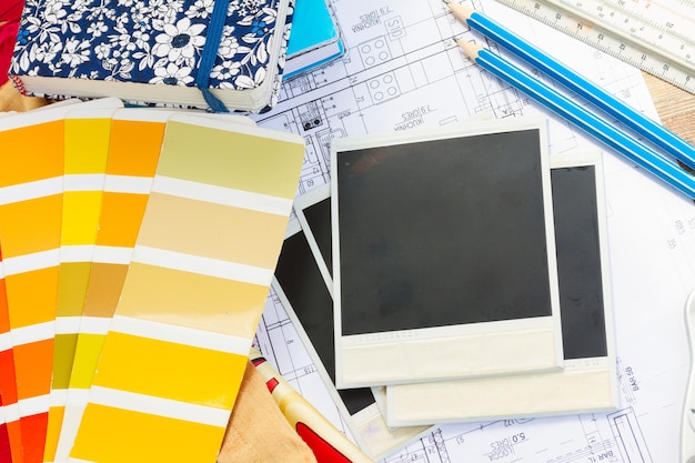 Interior designers working table, an architectural plan of the house,  color palette guide and fabric samples in yellow shades, copy space on instant empty photos