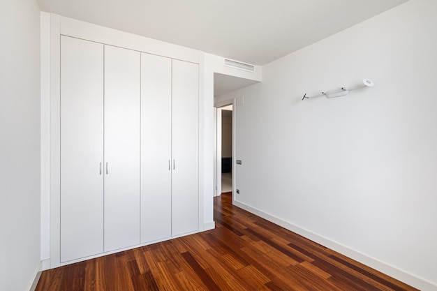 Interior of empty apartment white room with builtin wardrobe and parquet floor