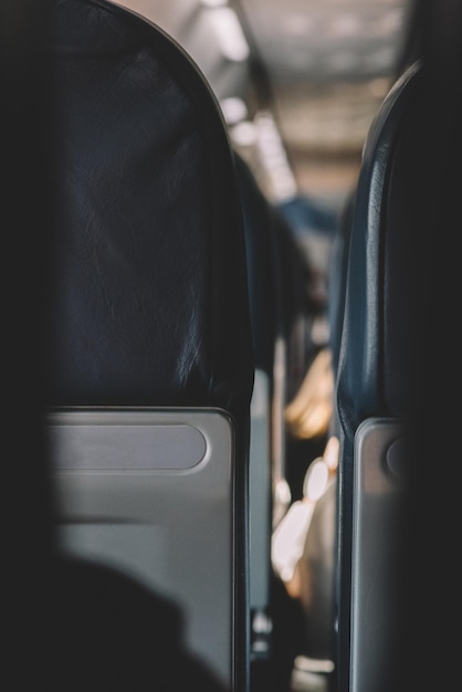 Interior of empty modern aircraft with blue flight seats and hallway in daytime during flight