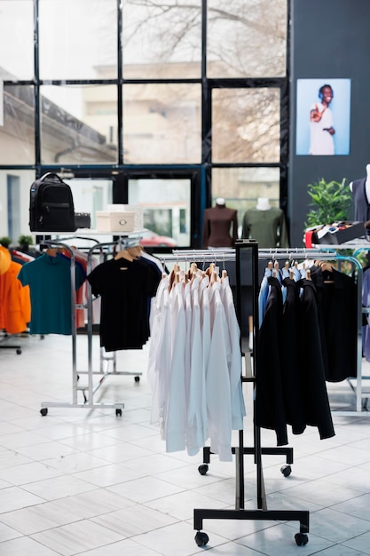 Interior of fashionable boutique with clothes on hangers, stylish brand design and formal wear in modern showroom. Empty clothing store in shopping center with trendy merchandise, commercial activity.