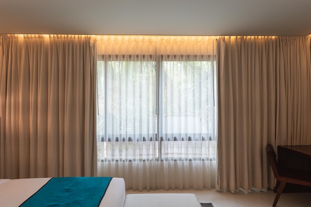 Interior of hotel room with lighting on beige curtain in bedroom