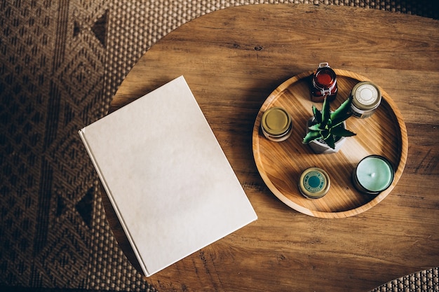 Interior items: candles, aromatic sachets, aloe flower on a wooden round stand on a wooden table. Cozy home concept Hardcover Book