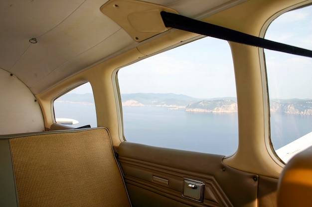 Interior of light aircraft in flight with view from the window of the coast of Mallorca