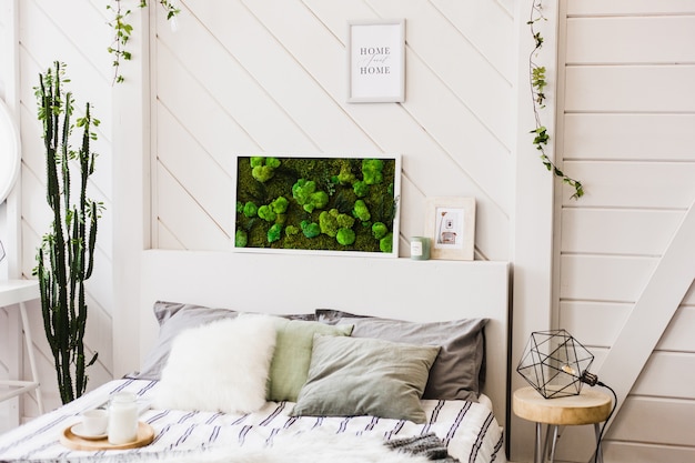 Interior light wall with a picture of moss, white walls, plants, candles and frames , bed , home and comfort