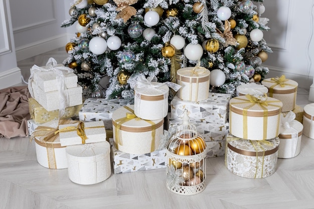 Interior of living room with a Christmas tree and decorations Beautiful Christmas tree with festive gold white decor Christmas and New Year concept present boxes and gifts