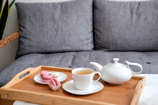 Interior of living room with cup of tea on a serving tray on a coffee table sofa houseplant Cozy concept