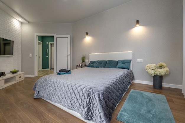 Interior of the modern luxure bedroom in studio apartments in gray light color style and green pillows