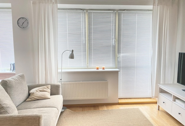 The interior of the room in white tones with a sofa TV and bedside lamp