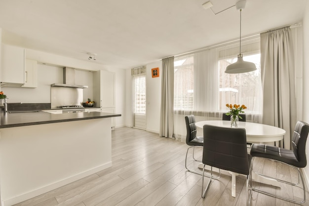 Interior of a small corner kitchen and a dining area in white in a cozy house