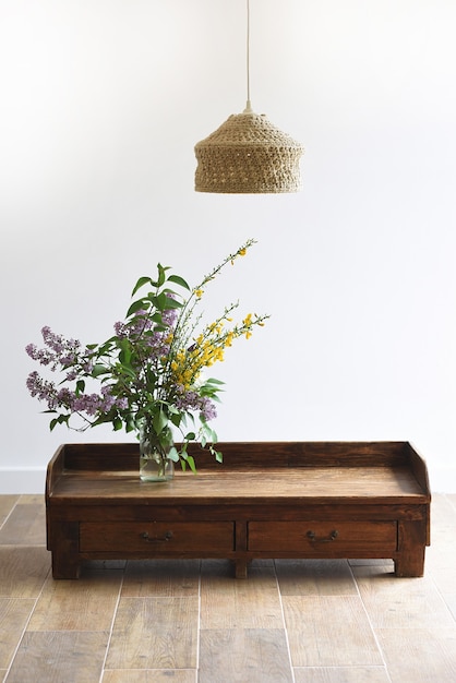 Interior space with lamp, wooden table and vase with wild flowers