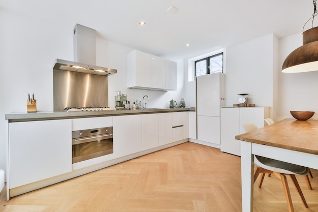 Interior of spacious kitchen with white cabinets and stainless extractor hood and black counter