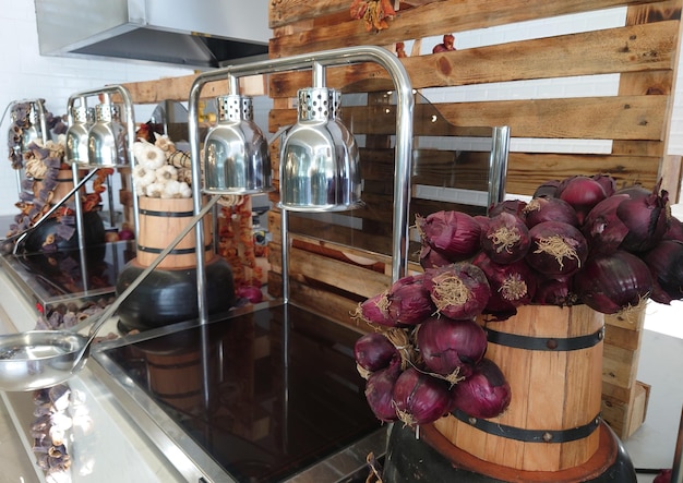 Interior of an upmarket restaurant with buffet counters with heated trays for serving and decor of dried fresh vegetables on wooden barrels