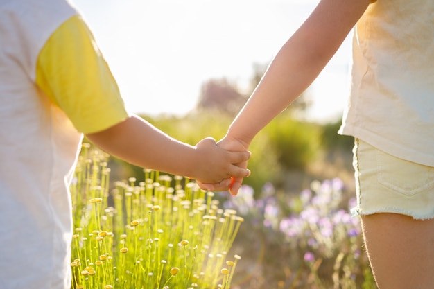 Interlocking hands of a boy and a girl in front of a green field