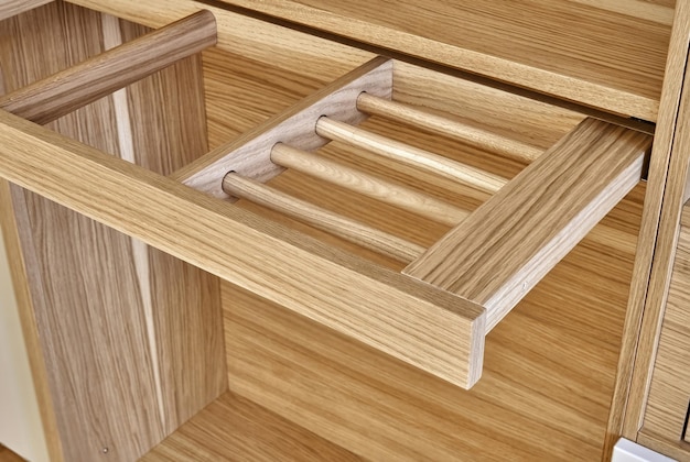 Internal details of wooden wardrobe with slide out rack for coathanger and light gray cabinet doors