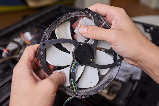 Internal parts of an old personal computer Dusty motherboard video card and fan The master cleans the PC cooler from dust Broken PC