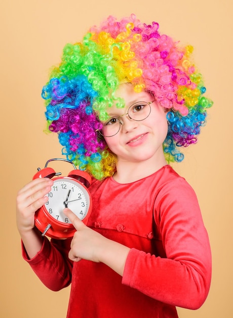 International childrens day Child care Happy moments Kid hold alarm clock Stop being so serious Girl cute playful kid wear curly rainbow wig Life is fun Happy childhood Happy little girl